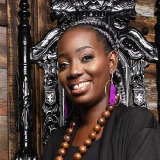 Atinuke Osibogun Adeleke smiling at the camera, carved wood background