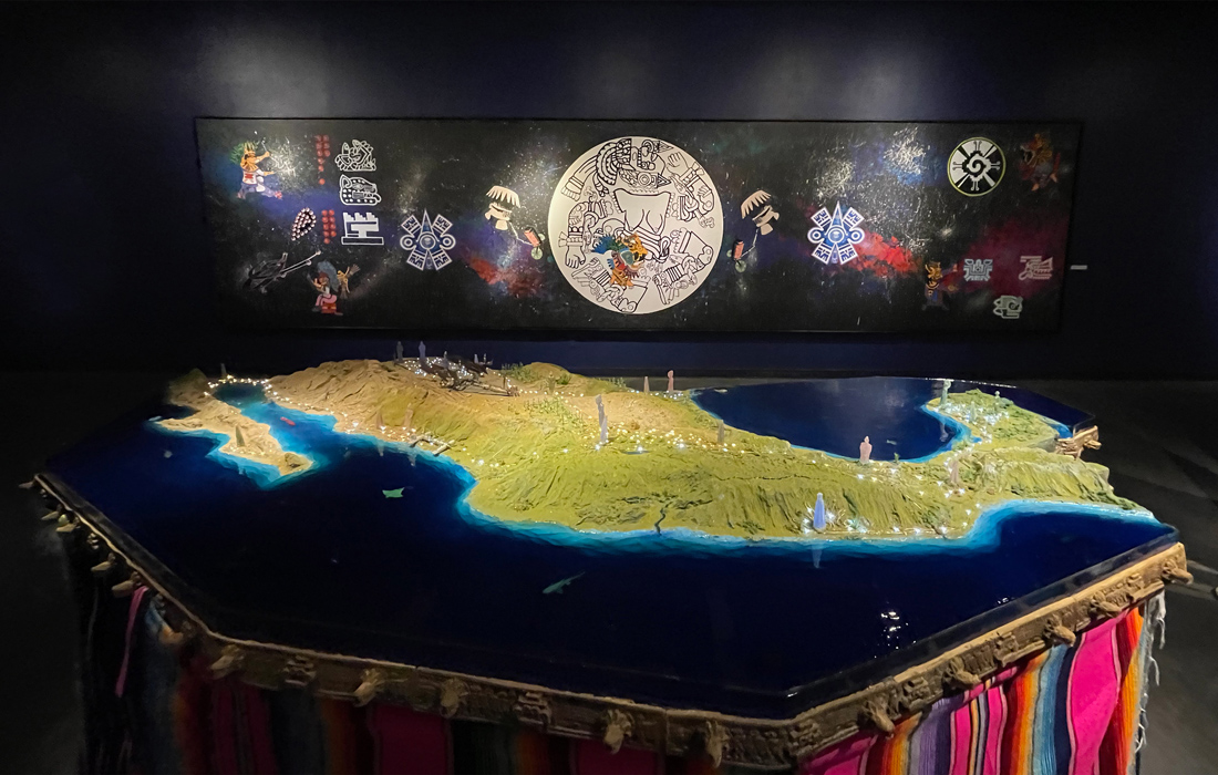 Map of Mexico on a table with a depiction of the moon on the wall behind it.