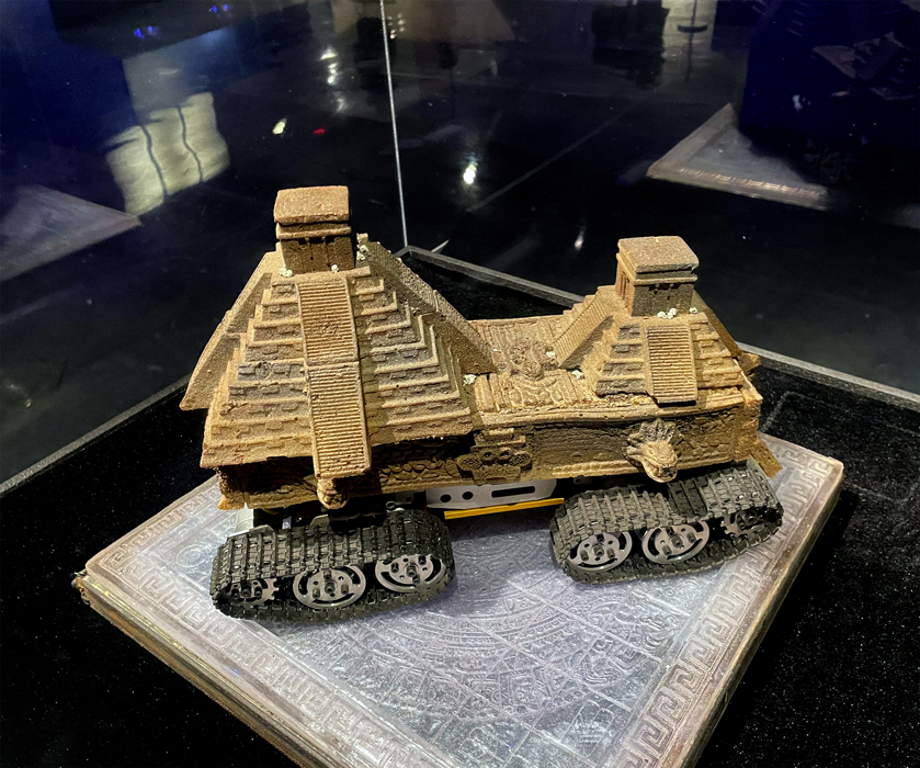 A sculpture of the Chichen Itza pyramid of Mexico mounted on tank's road wheels and track.