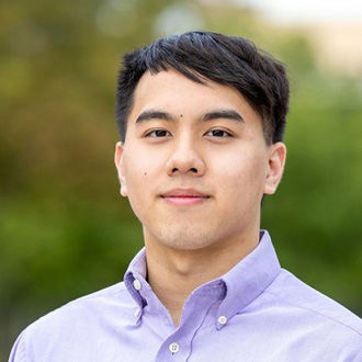 John Paul smiling, short dark hair, lavender button-down shirt