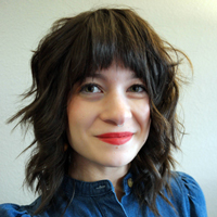 Naomi smiling, short dark hair, denim top.