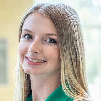 Marcy smiling at the camera, long blonde hair, green top