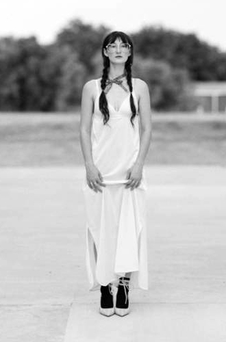 Tierani Bryan standing, facing forward, wearing a long dress, long braids and glasses.