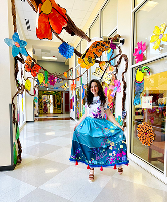 Keisha in a hallway with colorful art project on the walls and hanging from the ceiling