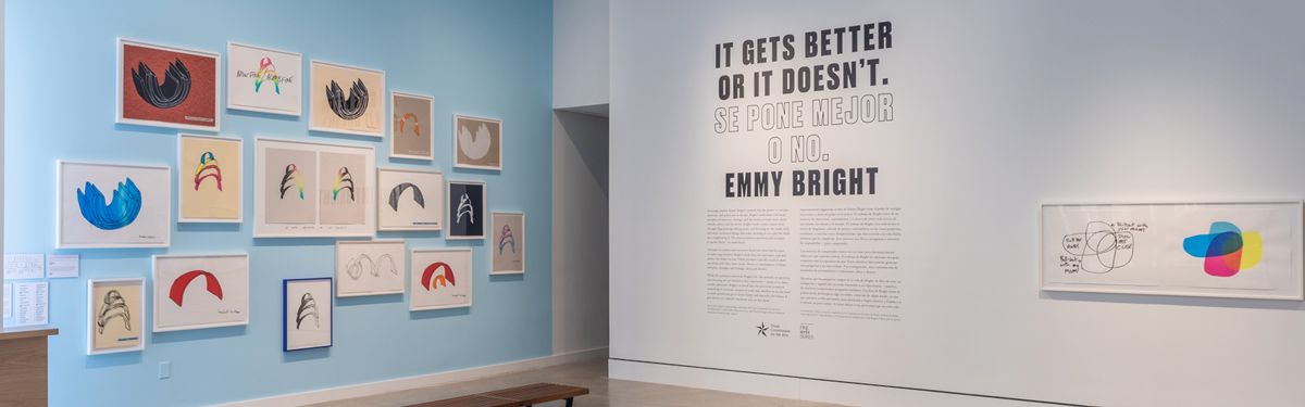 Interior view of the exhibition by Emmy Bright, framed prints on a blue wall.