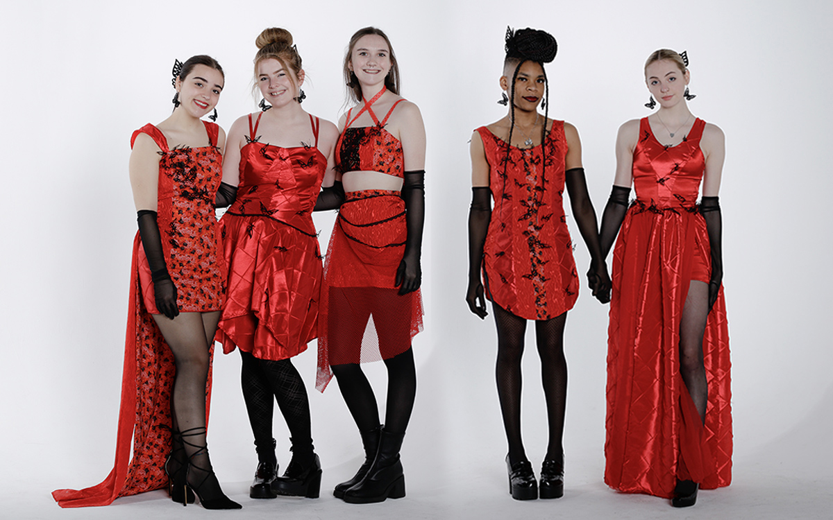 Collection shoot of five red floor length dresses on five female models standing in a line.