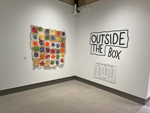 Outside the Box title on the wall next to a colorful quilt