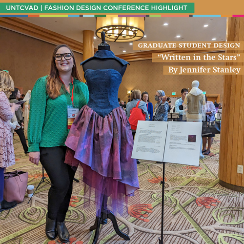 Jennifer Stanley posing next to a purple and dark blue dress she designed.