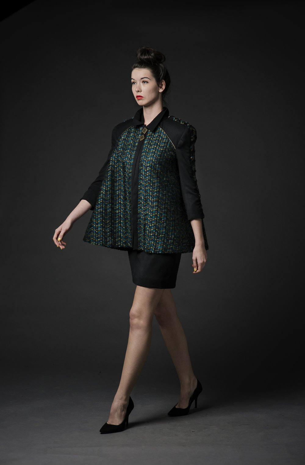 Woman modeling a black dress and a green jacket