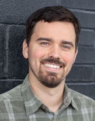 Michael Flanagan smiling, brown hair, green plaid shirt