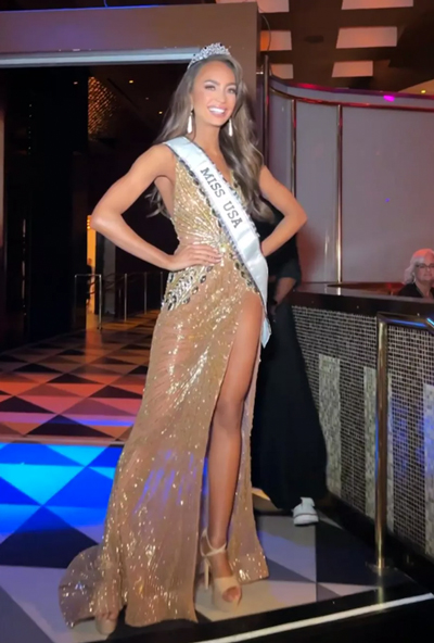 R'Bonney Gabriel in a gold evening gown wearing the Miss USA sash and crown