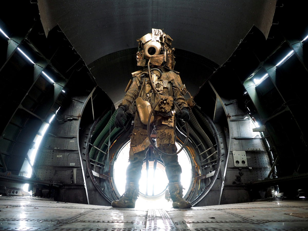 A spacewalker in a golden suit plastered with electronic circuits and other digital debris.