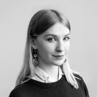 Three-quarter view of Ella smiling, long hair, sweater over a button-up shirt