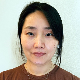 Wei facing forward, dark hair pulled back, rust-colored shirt