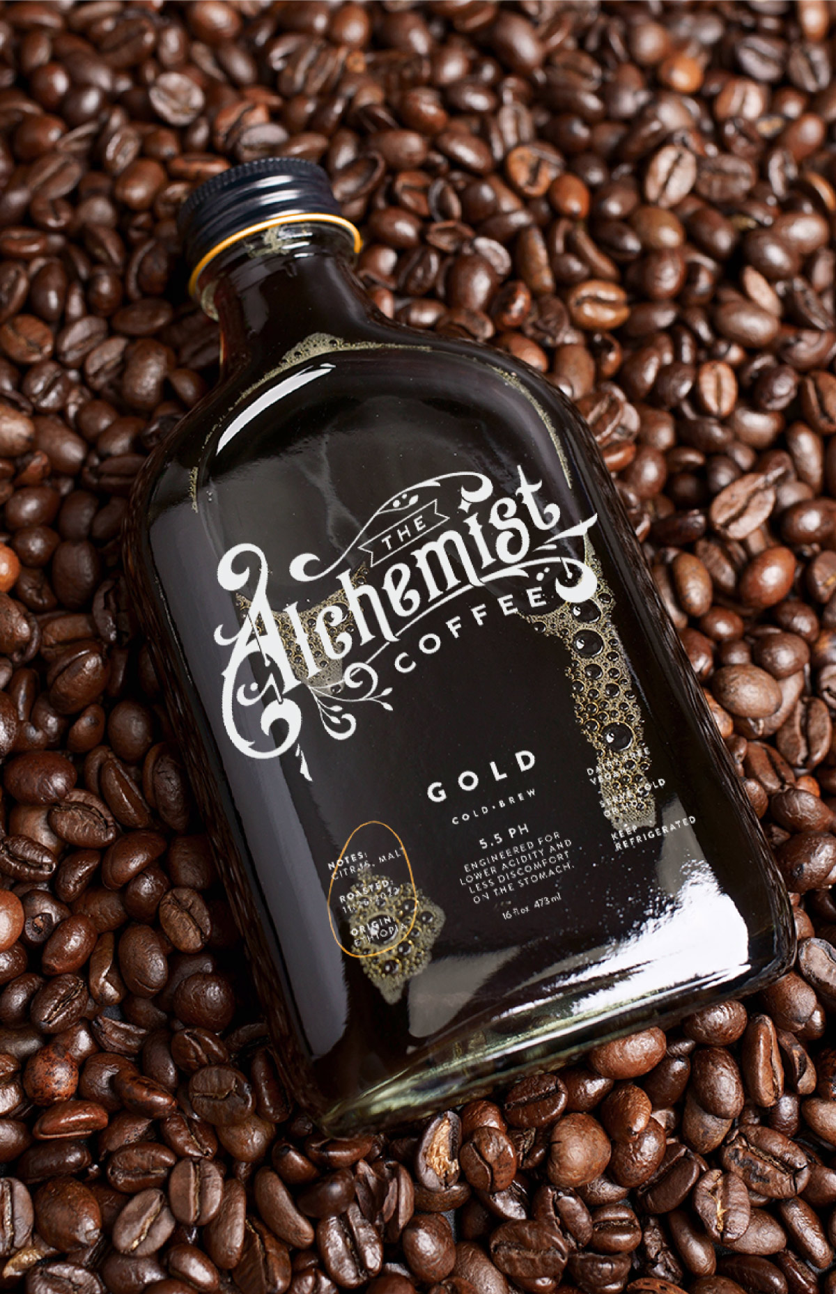 Glass coffee bottle with a vintage packaging laying on a bed of coffee beans