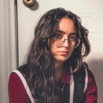 Madi with long dark brown hair, round glasses, and a red, black, and white shirt