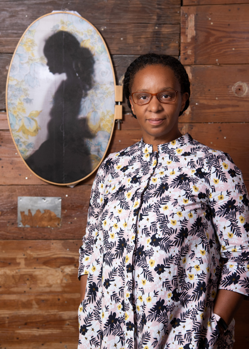 Letitia standing next to a photo on fabric in an oval frame.