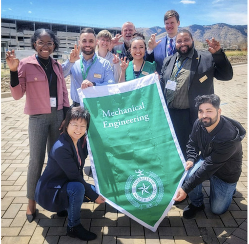 Group of nine Engineering and Design students and two faculty advisors making the eagle claw hand sign