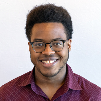 Jalon Isabell facing forward, smiling, dark hair, glasses, maroon-colored shirt