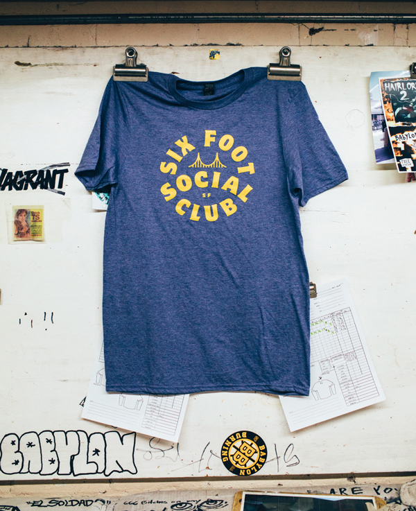 Blue T-shirt clipped to a wall; writing says "Six Foot Social Club."