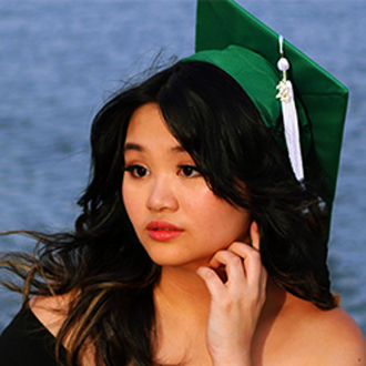 Three-quarter view of Emily with long hair and a green graduation cap