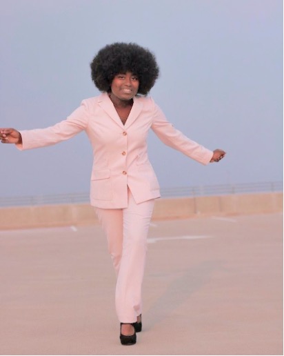 Kennedy in a dance move with her arms out, wearing a pink suite