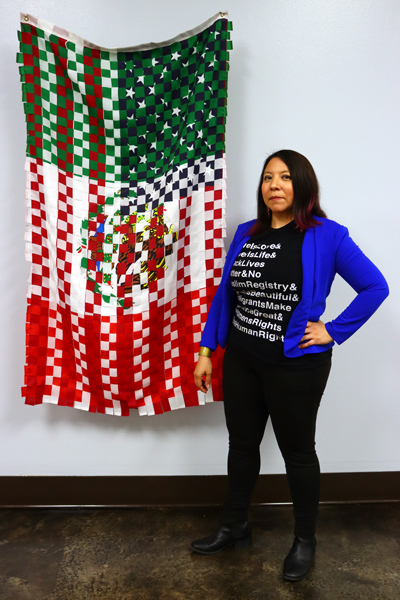 Tina standing next to her art titled "Bandera," a single flag woven of the Mexican and American flags.