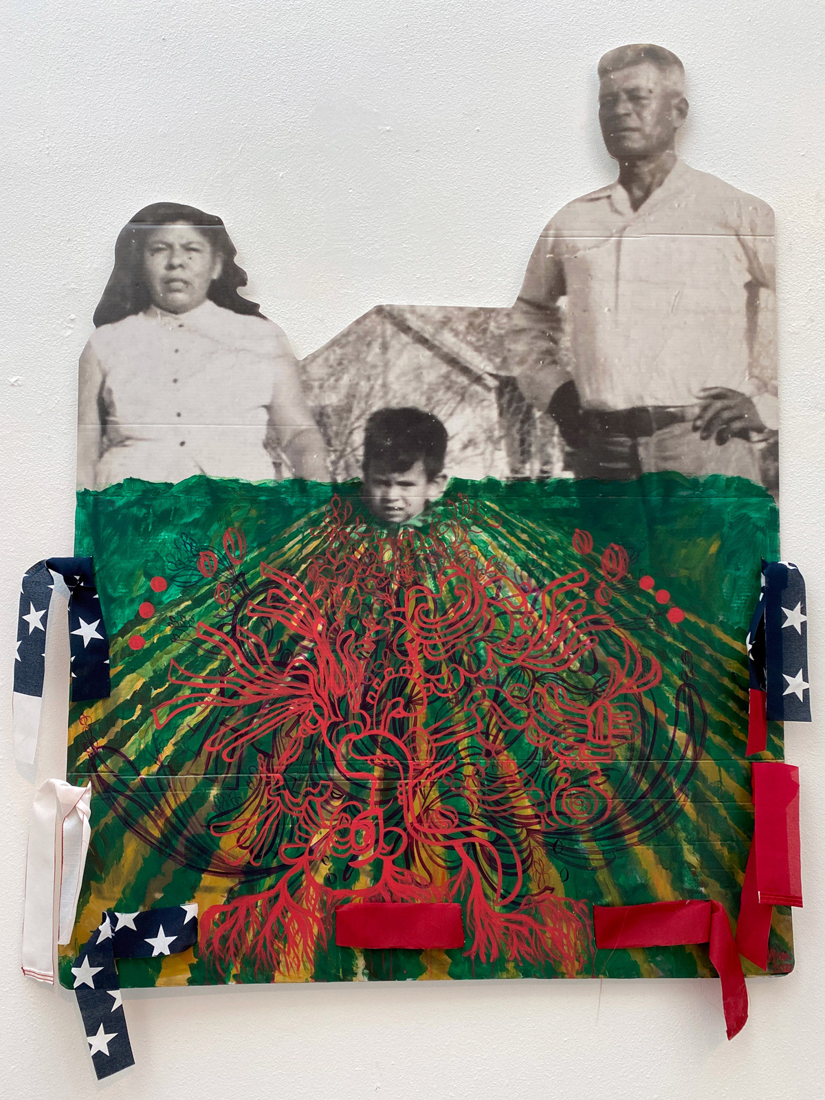 Image of a two hispanic adults and a child in front of a green farm field
