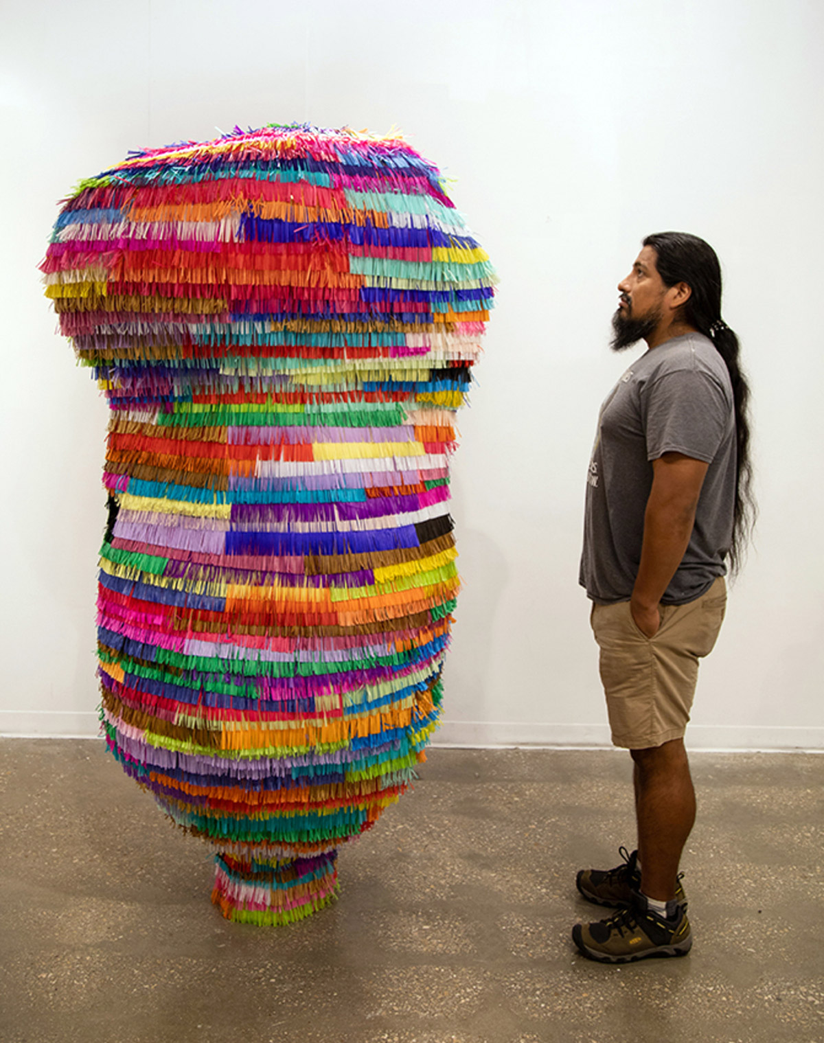 Saxon standing next to a tall sculpture covered in colorful strips of tissue paper