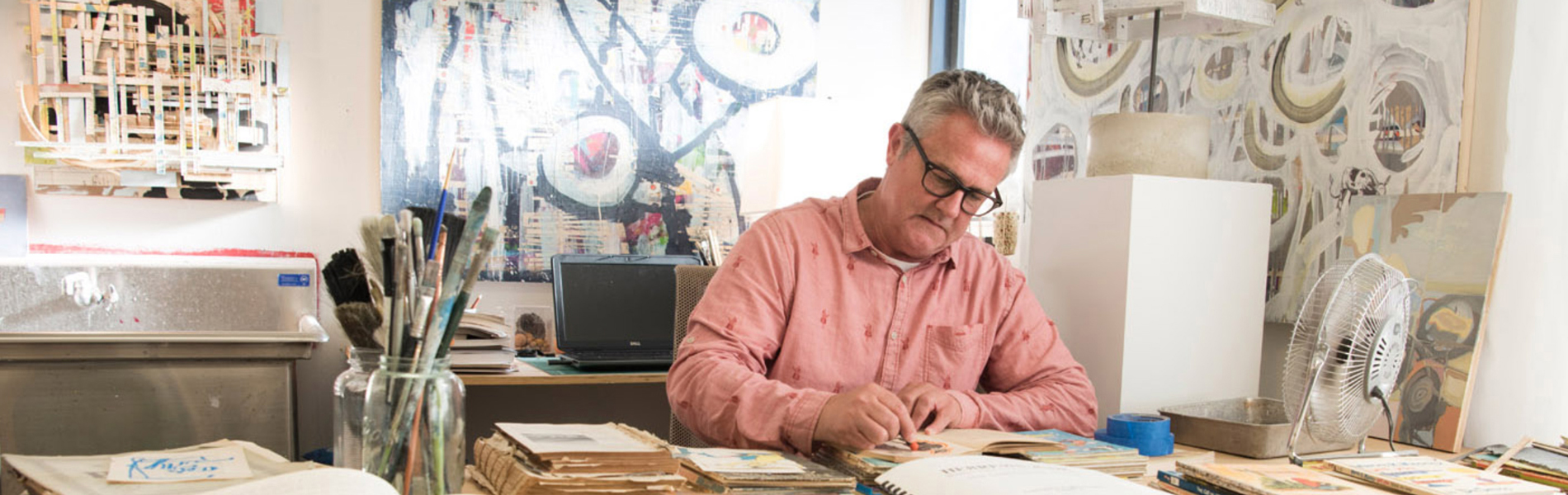 Jim Wilson sitting at a table working in his studio.