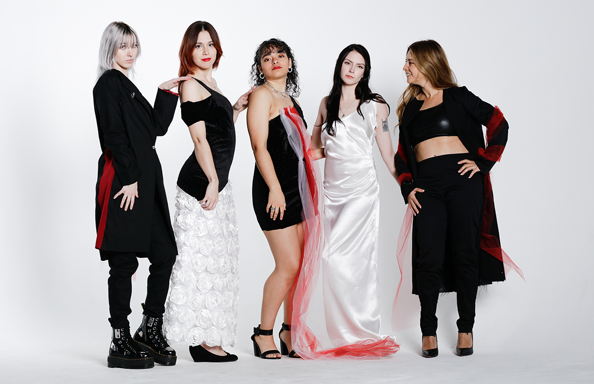 An image of 5 models standing and wearing black and red outfits posing for a photoshoot.