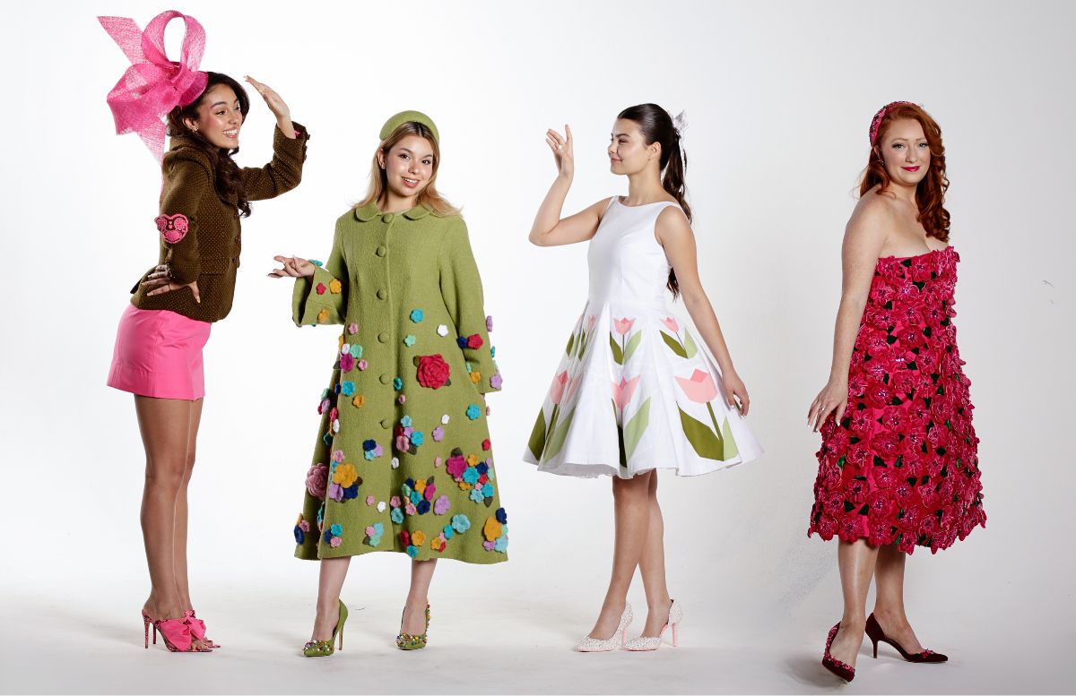 Four models standing in a line, three of them are wearing dresses made ofdifferent floral style fabrics and one is wearing a pants and suit combination.