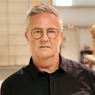 Jim with gray hair, wearing a black shirt, round glasses