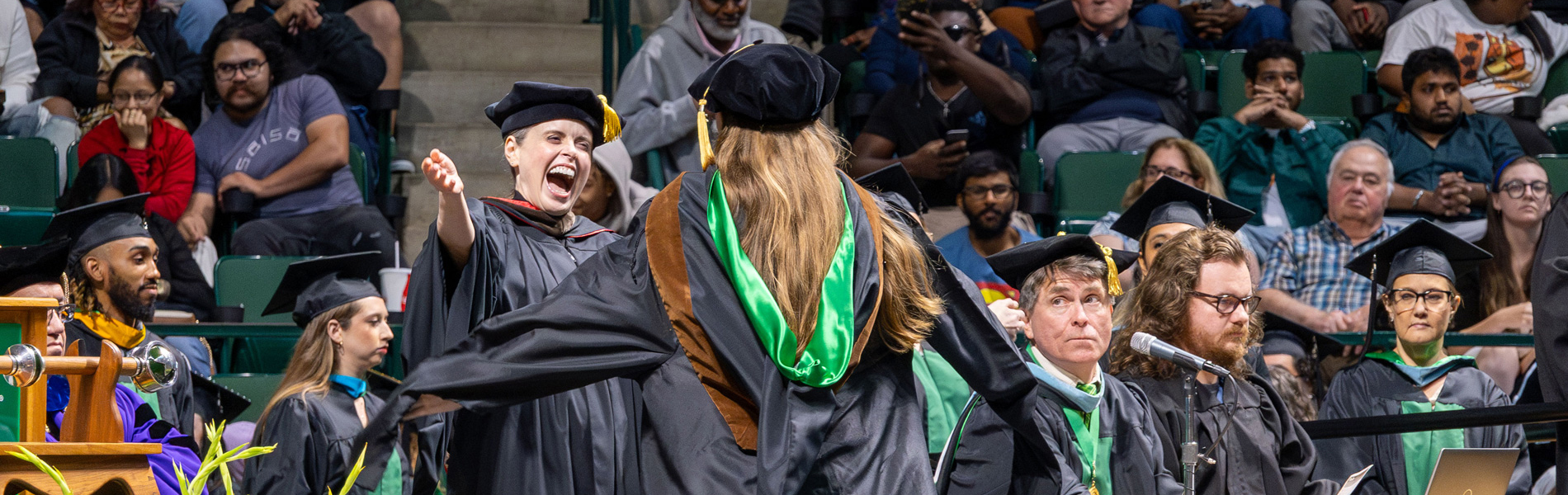 Professor Gibbons with her arms wide open to hug a new graduate!