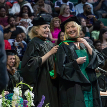Graduate student receiving their hood from their professor on stage at the Spring 2023 commencement ceremonies.