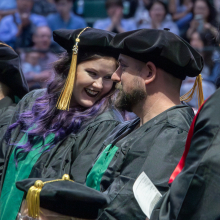 Graduate students excitedly waiting to walk across the stage to receive their diplomas at the Spring 2023 commencement ceremonies.