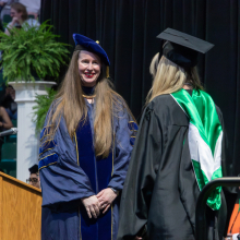 Two people on stage at commencement in regalia