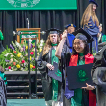 Graduate student waiving to family after receiving diploma for M.A. in Art History at the Spring 2023 commencement ceremonies.