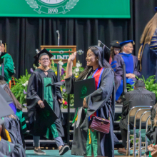 Graduate student waiving to friends and family after receiving diploma for M.A. in Art History at the Spring 2023 commencement ceremonies.