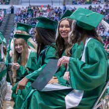 Undergraduate students smiling in their seats after walking across the stage to receive their diplomas at the Spring 2023 commencement ceremonies.