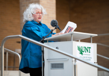 Debbie Stafford speaking at the podium in the UNT Art Building Courtyard