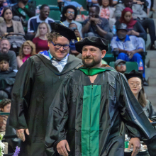 Graduate student Eric Grasham walking across the stage to receive his M.F.A. in Studio Art: Ceramics at the Spring 2023 commencement ceremonies.