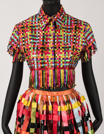 Detail of a cropped shirt made of tightly woven rainbow-colored narrow satin ribbons with fringe created from the ribbon ends and accented with multicolored pony beads.
