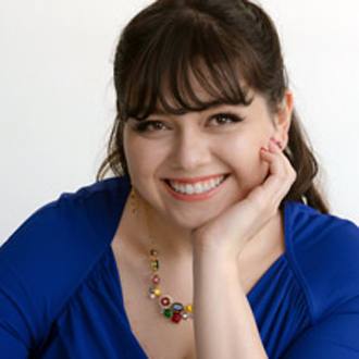 Gabrielle smiling, chin leaning on her hand, dark long hair, blue shirt